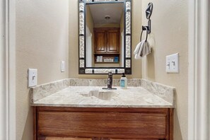 A bathroom with a marble sink, wooden vanity, and a mirror with a decorative frame. - Waterfront Home With Kayak, View, Fire Pit & Wifi - Dog-friendly (Buchanan Dam)