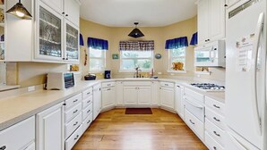 A kitchen with white cabinets, a microwave, a stove, and a refrigerator.