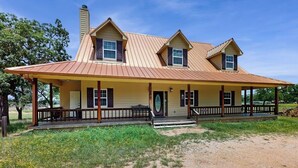 A two-story house with a covered porch, a chimney, and a front door.