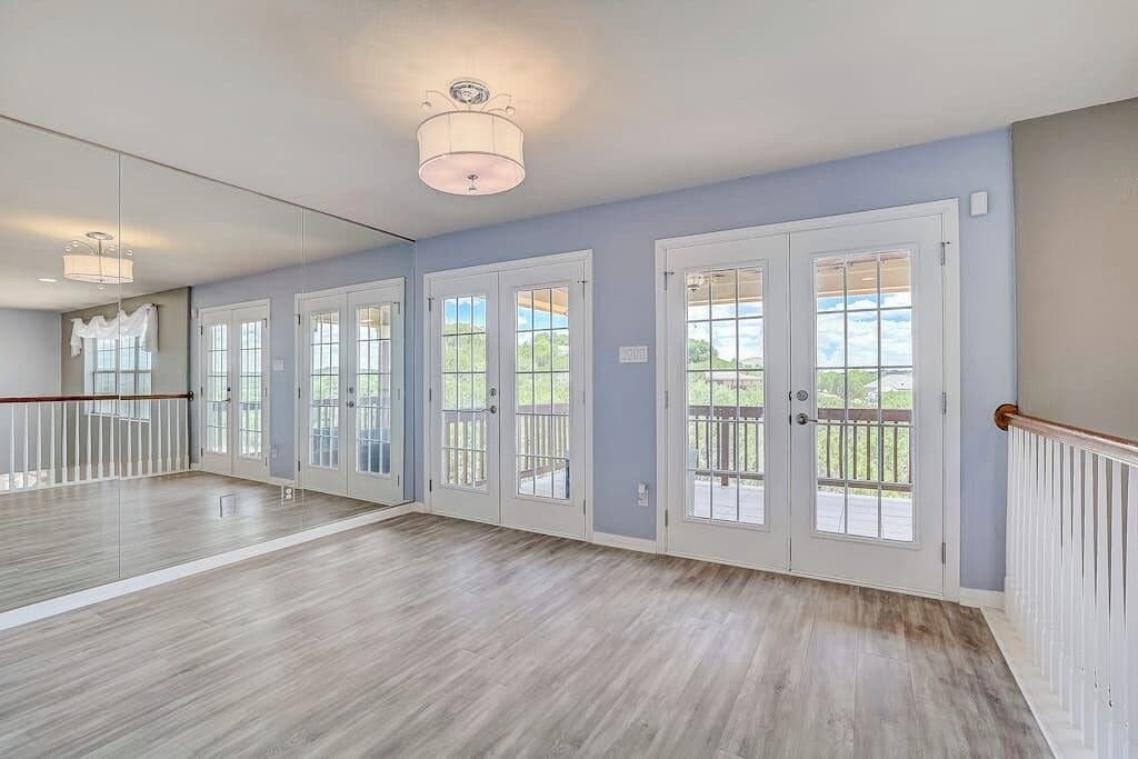 Una habitación amplia con piso de madera, ventanas grandes y un balcón.