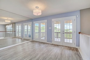 Una habitación amplia con piso de madera, ventanas grandes y un balcón.