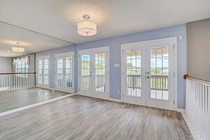 Um quarto espaçoso com piso de madeira, grandes janelas e uma varanda.