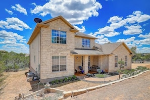 A two-story house with a stone facade, large windows, and a satellite dish. - Spacious, Dog-friendly Home With Two Decks, Views, Grill, W/D & Community Pool (Leander)