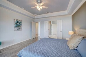Un dormitorio con cama, ventilador de techo, puerta y lámpara fijada a la pared.