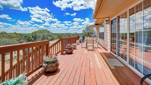 A wooden deck with potted plants, a seating area, and a view of the landscape. - Spacious, Dog-friendly Home With Two Decks, Views, Grill, W/D & Community Pool (Leander)