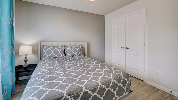 A bedroom with a bed, a nightstand, a ceiling fan, and a door. - Spacious, Dog-friendly Home With Two Decks, Views, Grill, W/D & Community Pool (Leander)