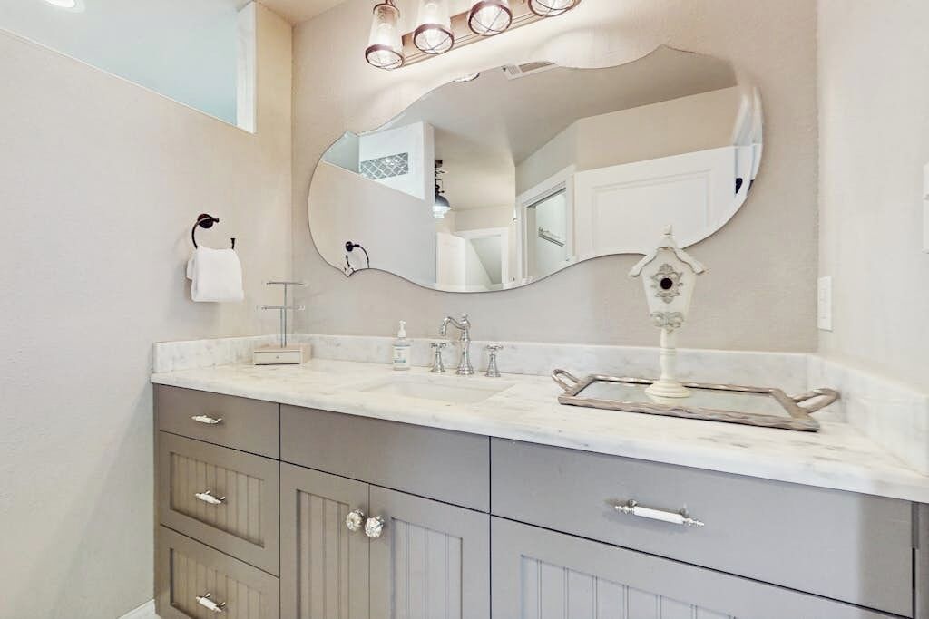 Une salle de bain avec un grand miroir, un lavabo et un meuble-lavabo doté de tiroirs.
