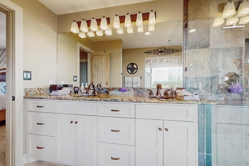 Un baño con un espejo grande, varios lavamanos y un mueble tocador con cajones.