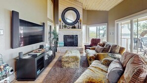 Un salon spacieux doté d’une cheminée, d’un grand téléviseur à écran plat et d’un coin salon confortable.