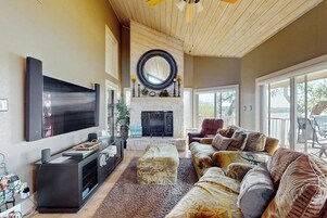 Un salón espacioso con chimenea, un televisor de pantalla plana grande y una zona de estar cómoda.