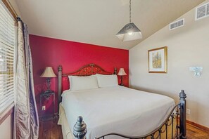 A bed with a headboard, two bedside lamps, a hanging light fixture, a framed picture on the wall, and a window with curtains. - Lovely Dog-friendly Suite With Tasting Rooms Along Hwy 290 Wine Trail (Fredericksburg)