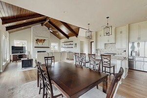 Cozinha espaçosa com pé direito alto, área de jantar com uma grande mesa de madeira e ilha moderna.