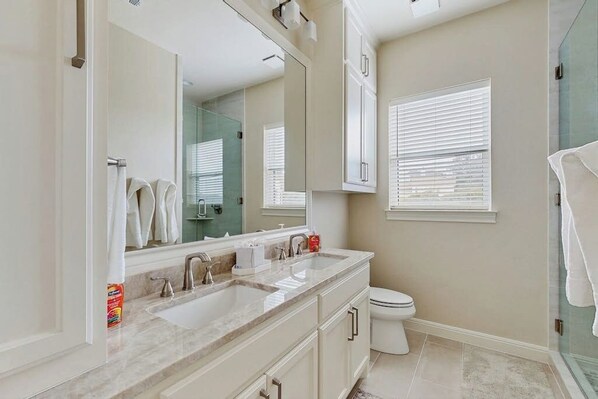 A modern bathroom with a large mirror, two sinks, a toilet, and a shower area. - Spacious House With Ping-pong and Pool Table, Balcony With Water and Sunset View (Leander)