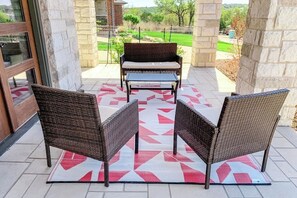 Un patio con mobiliario de mimbre, un tapete estampado y vistas a un paisaje verde.