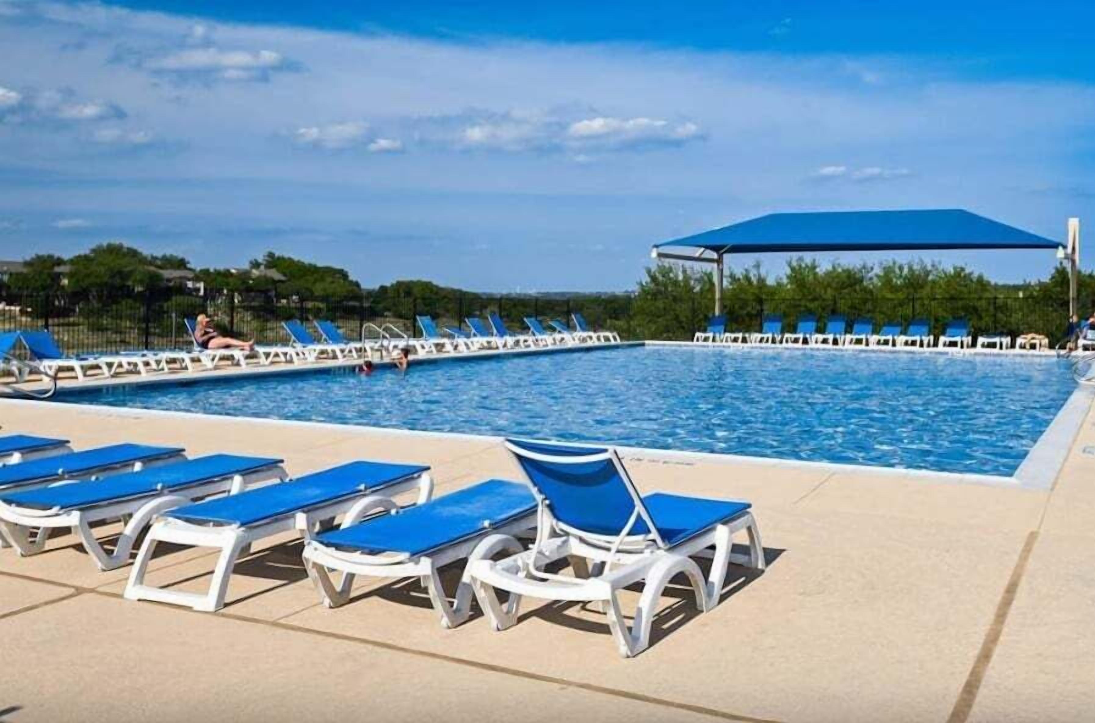 Un área de piscina con múltiples tumbonas y una zona de estar cubierta.