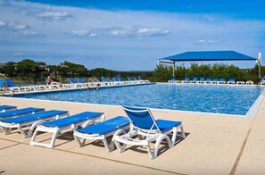 Un área de piscina con múltiples tumbonas y una zona de estar cubierta.
