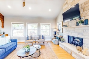 A living room with a fireplace, a television mounted on the wall, and a sofa. - Bright & Spacious Family Home With Firepit, Lake Views, Furnished Deck, Free Wifi (Leander)