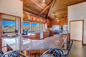 Una cocina amplia con encimeras de granito, armarios de madera y una isla grande.