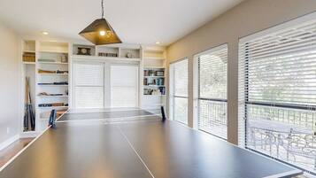 Una mesa de ping pong en una habitación con una estantería, un reloj y un letrero que dice 'LIVING ROOM'.