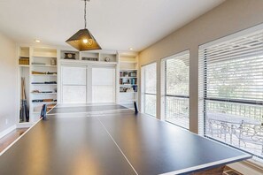 A ping pong table in a room with a bookshelf, a clock, and a sign that reads 'LIVING ROOM.' - Spacious Lakefront Hideaway With Decks, Grill, Billiards, Tennis & Pool (Spicewood)