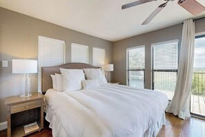 A bedroom with a large bed, two bedside tables with lamps, and a ceiling fan. - Spacious Lakefront Hideaway With Decks, Grill, Billiards, Tennis & Pool (Spicewood)
