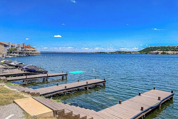 A waterfront dock with boats, a clear sky, and buildings in the background. - Contemporary, Dog-friendly Townhouse With Balcony, Pool & Day Docks (Horseshoe Bay)