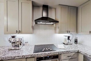 A kitchen with a built-in stove, espresso machine, and a hood vent. - Contemporary, Dog-friendly Townhouse With Balcony, Pool & Day Docks (Horseshoe Bay)