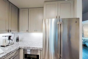A modern kitchen with stainless steel appliances, a herringbone-patterned backsplash, and light-colored cabinetry. - Contemporary, Dog-friendly Townhouse With Balcony, Pool & Day Docks (Horseshoe Bay)