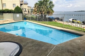 A rectangular swimming pool with a metal fence, a palm tree, and a view of the water. - Contemporary, Dog-friendly Townhouse With Balcony, Pool & Day Docks (Horseshoe Bay)