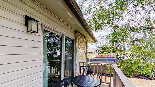 A covered outdoor area with a table and chairs, a stone pillar, and a glass door. - Contemporary, Dog-friendly Townhouse With Balcony, Pool & Day Docks (Horseshoe Bay)