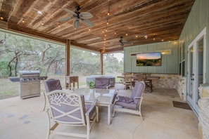 Eine Terrasse im Freien mit Grill, Sitzgelegenheiten und einem an der Wand befestigten Fernseher.