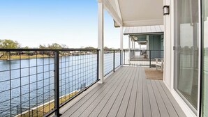 Ein überdachter Balkon mit Blick auf einen Fluss, einem Geländer und einer Sitzbank.