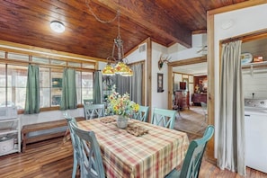 A dining area with a wooden ceiling, a table with a plaid tablecloth, and chairs. - Historic Lakefront & Wildlife Haven With Firepit & Gas Grill - Minutes to Water (Burnet)