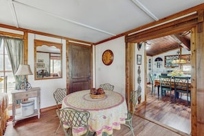 A dining area with a round table, chairs, a lamp, and a clock on the wall. - Historic Lakefront & Wildlife Haven With Firepit & Gas Grill - Minutes to Water (Burnet)