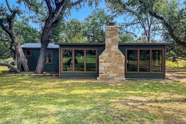 A modern house with large windows and a stone chimney. - Historic Lakefront & Wildlife Haven With Firepit & Gas Grill - Minutes to Water (Burnet)