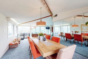 Ein geräumiger Essbereich mit einem langen Holztisch, orangefarbenen Stühlen und Pendelleuchten.