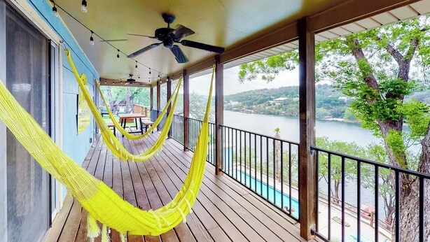 Eine Holzterrasse mit einer Hängematte, einem Deckenventilator und Blick auf einen See.