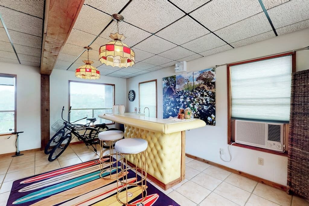 A kitchen with a bar area, a bicycle, and a large window.