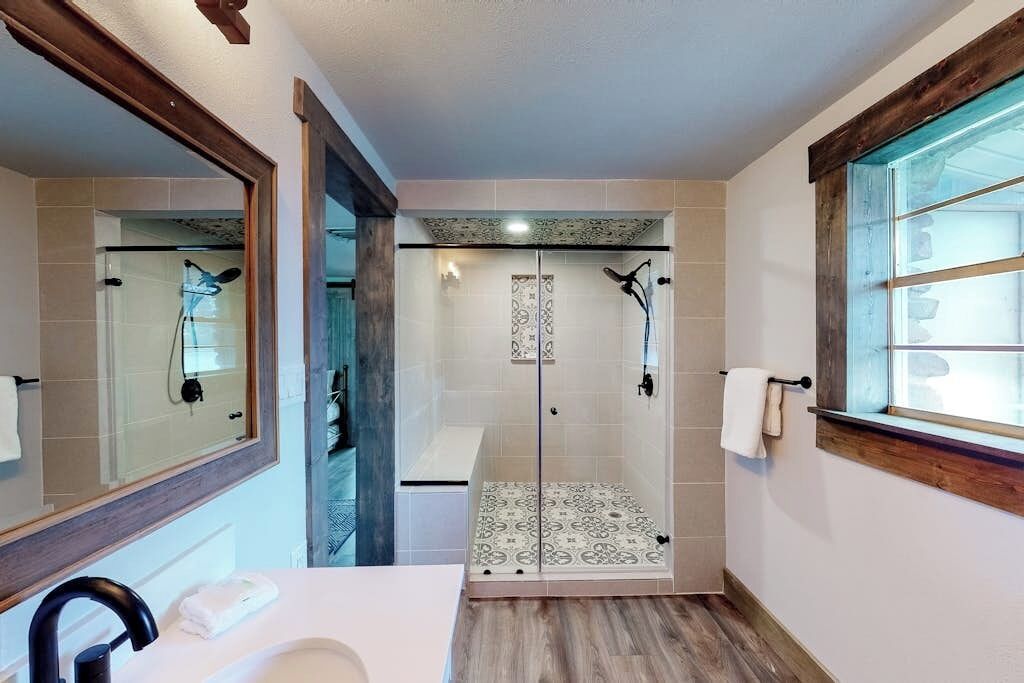 Un baño con ducha, lavamanos y ventana.
