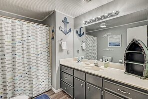 A bathroom with a grey and white color scheme, a large mirror, a vanity with a sink, and a shower curtain with a fish pattern. - Dog-friendly Water View Condo With Inviting Porch, AC, W/d, & Modern Charm (Horseshoe Bay)