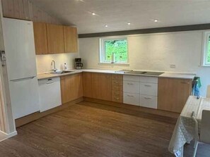Een moderne keuken met houten kastjes, een vaatwasser en een raam dat voor natuurlijk licht zorgt.