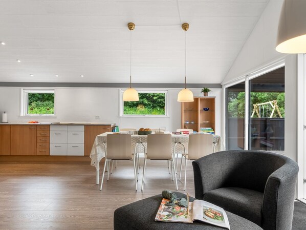 A modern kitchen with a dining area, large windows, and a cozy seating area.