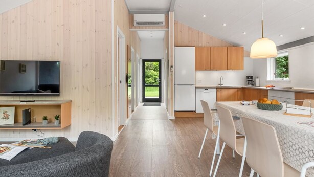Une cuisine moderne avec des meubles en bois, un four encastré et un coin repas comprenant une table et des chaises.