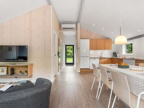 A modern kitchen with wooden cabinets, a built-in oven, and a dining area with a table and chairs.