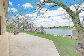A patio with chairs, a pool, and a building with a stone facade. - Lakeside, Dog-friendly Living With Kayaks, Boat Ramp, Pool Table & Ping-pong (Kingsland)