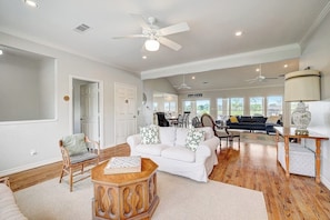 A spacious living room with a white sofa, wooden coffee table, and a dining area in the background. - Lakeside, Dog-friendly Living With Kayaks, Boat Ramp, Pool Table & Ping-pong (Kingsland)