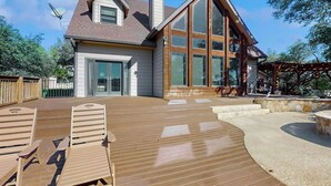 Une maison dotée d’une grande terrasse, d’une cheminée et d’une pergola.