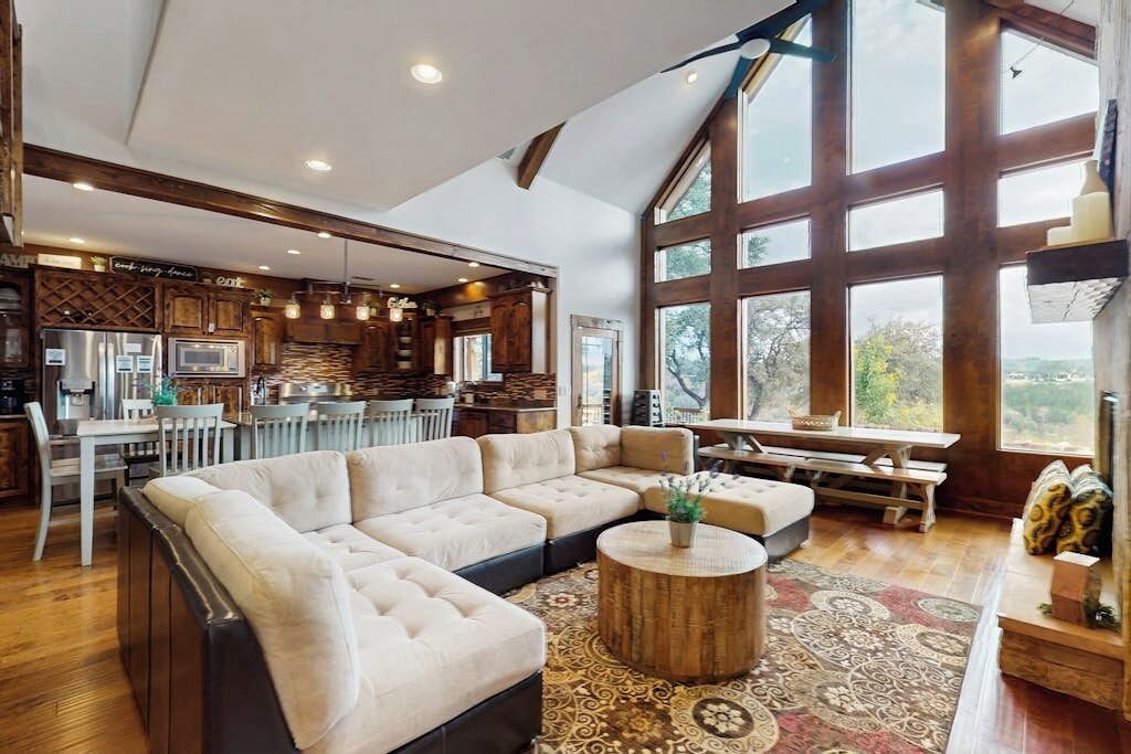 A spacious living area with a large sectional sofa, a round coffee table, and a view through large windows.