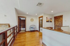 Un pasillo con piso de madera, un mostrador de recepción, una puerta de madera y un adorno en la pared.
