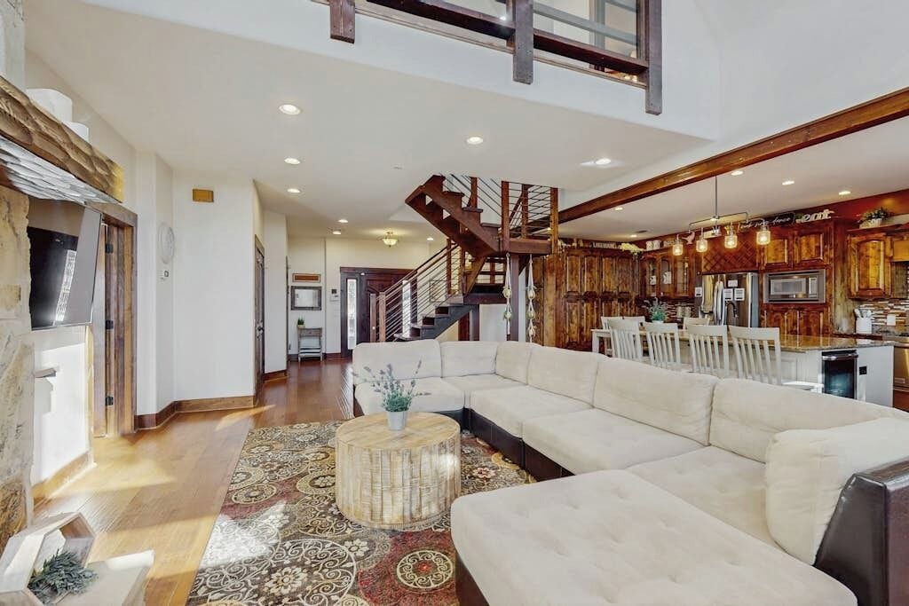 A spacious living area with a large sectional sofa, a round coffee table, and a patterned rug.